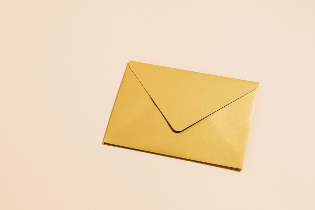 A sleek gold envelope placed on a vibrant yellow background, perfect for postal themes.